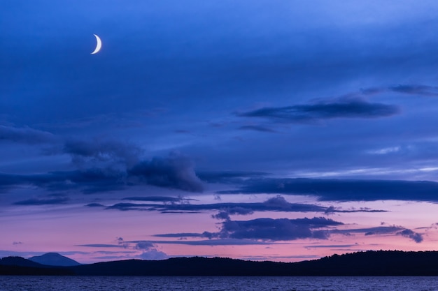 Big moon in blue sky over the lake in the evening