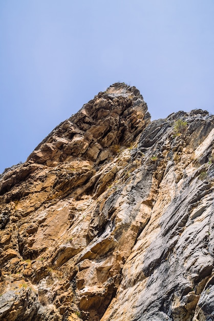 Big mountain cliff under cloudy sky close-up. 