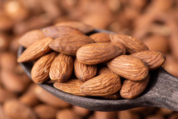 Big nuts of almond in dark wooden spoon