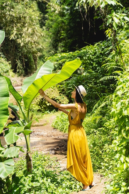 Big plants. Attractive brunette keeping eyes closed while enjoying sounds of nature during her walk