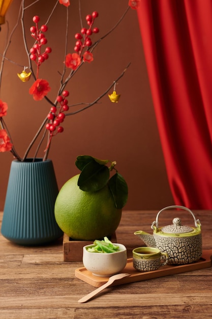 Big pomelo fruit teapot cup and candied fruits for spring festival on wooden table