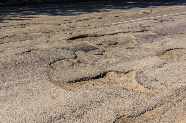 Big potholes on the damaged asphalt road