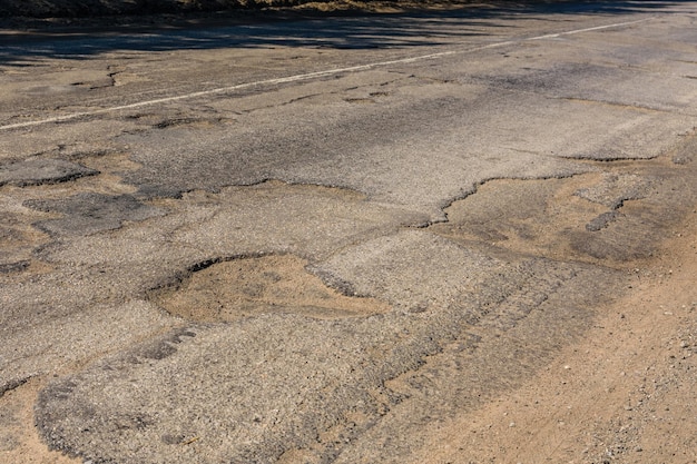 Big potholes on the damaged asphalt road