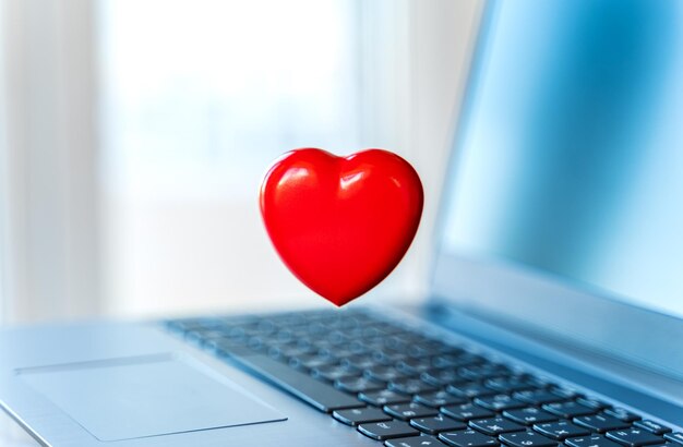 Photo big red heart on laptop keyboard valentine's day holiday concept online love remote communication on internet social networks virtual dating calls and technologyquarantinecoronavirus covid19