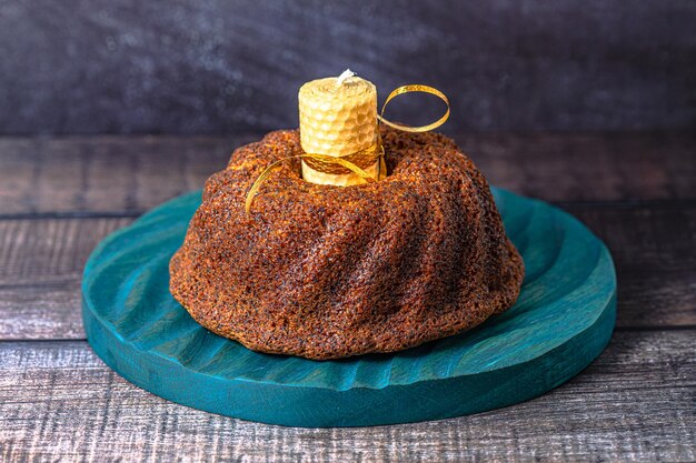 A big round cupcake on dark background with yellow candlex9xA