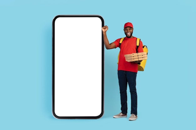 Big sale excited black pizza delivery guy celebrating success near blank smarthone