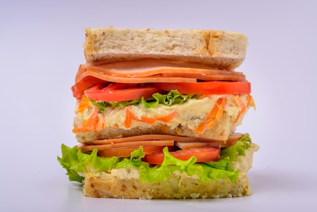 Big sandwich with smoked ham cream lettuce and tomato isolated on white background Fast food