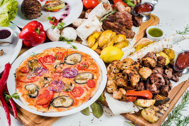 Big set of different dishes with meat vegetables pizza and spices flatlay on white background