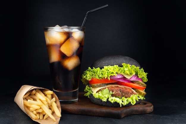 Big single cheeseburger with glass of cola and french fries