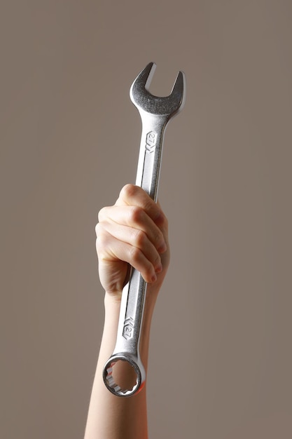 Photo big spanner in the womans hand hand holds a wrench on a gray background combination wrench big chrome vanadium spanner in the hand womens work labor day