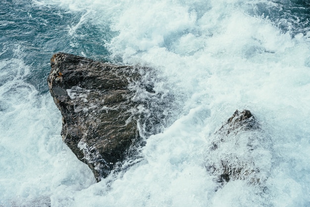 Big stones in azure water of mountain river close-up.