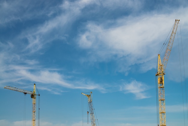 Big tower cranes against the blue sky. image of construction equipment close-up with copy space. Build of city.