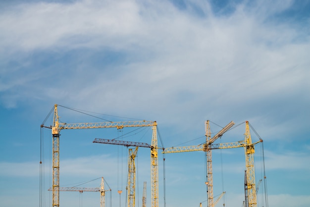 Big tower cranes against the blue sky. image of construction equipment close-up with copy space. Build of city.