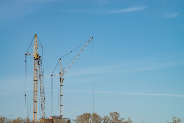 Big tower cranes against the blue sky.