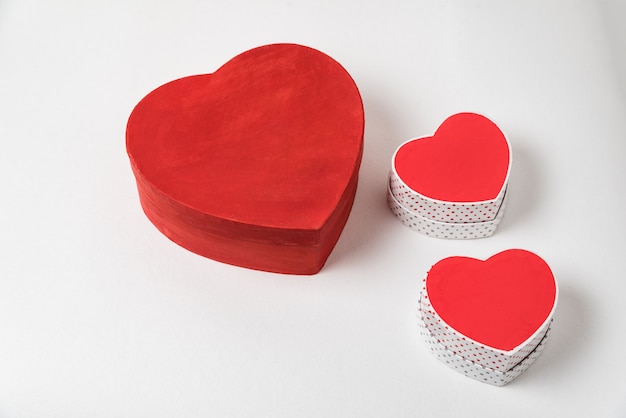 Big and two small red heart shaped boxes on table. Above view. Valentine's Day