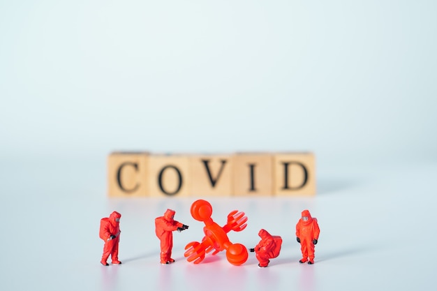 Big virus with a team of special medical forces miniature figurines, the team preparing for action against dangerous deadly virus type ,Wooden cubes with words 'covid' on white background.