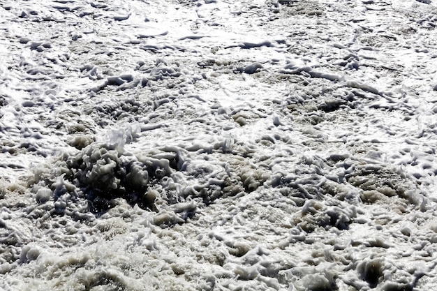 Big waves breaking on the shore with white forma