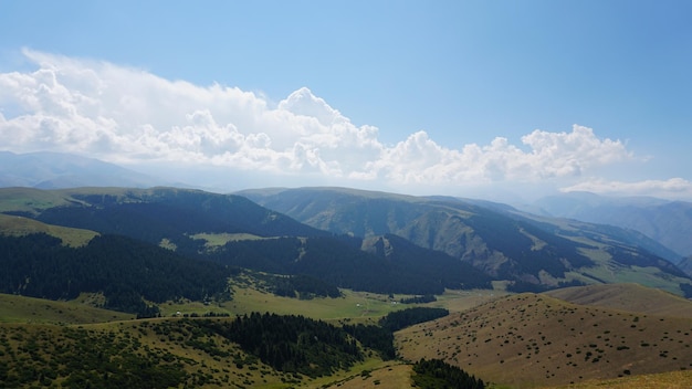 Big white clouds over green hills and mountains