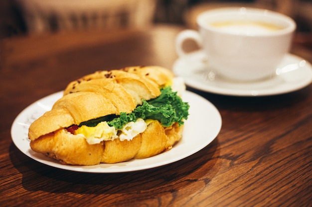 Big white cup of coffee and delicious croissant 