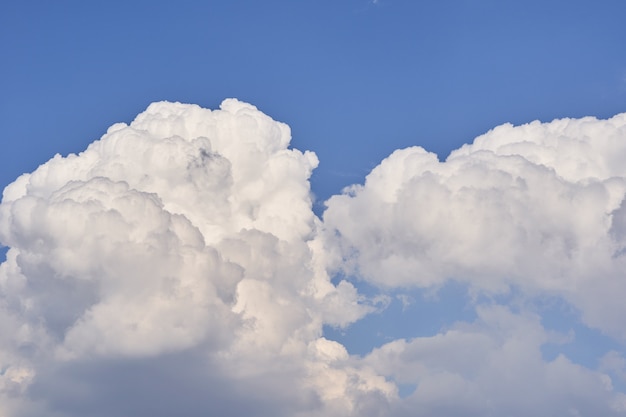 Big white fluffy cumulonimbus clouds floating on blue sky on bright sunny day