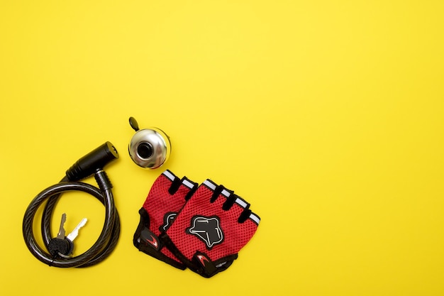 Bike lock bell and gloves on yellow background with copy space