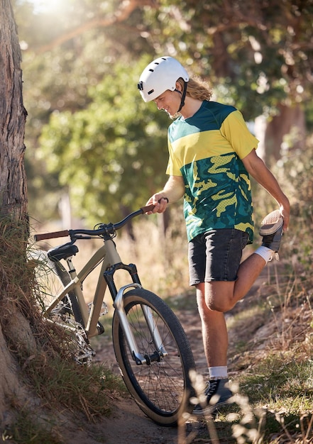 Bike nature and stretching with a man cyclist in the mountains for exercise cardio or adventure Fitness sports and cycling with a male athlete warming up with his bicycle in the forest or woods