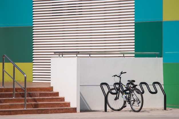 Photo a bike rack with a black bike parked next to a building with colorful walls.