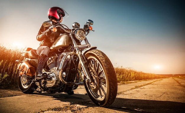 Biker girl on a motorcycle in a leather jacket and a helmet, looks at the way