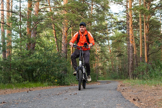 A biker riding through a trail among trees in the forest Active pastime Sports hobby a man on an electric bike in the park