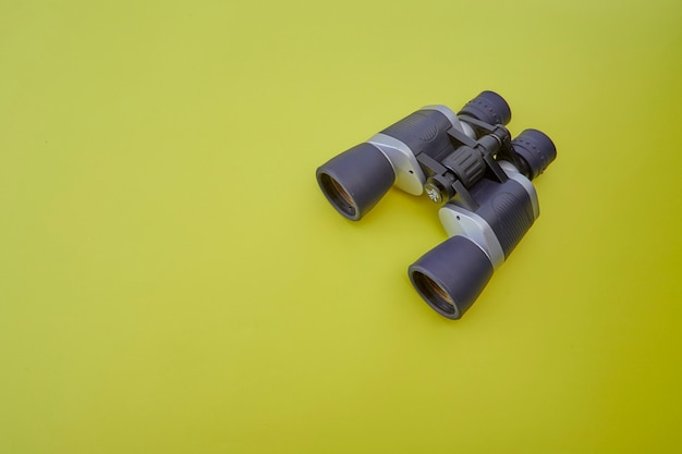 Binoculars silver and gray on yellow background