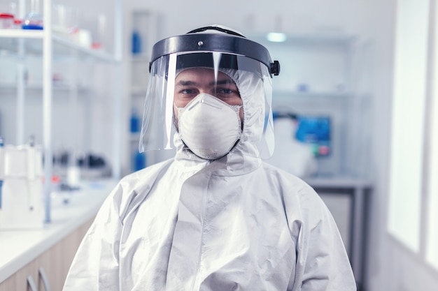 Biochemistry scientist wearing face mask and face shield as safety precaution for covid19 outbreak working in lab. Overworked researcher dressed in protective suit against invection with coronavirus d