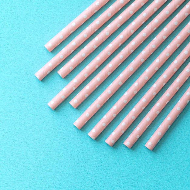 Biodegradable spotted pink paper straw set on blue table background design concept of environmental protection for Earth Day