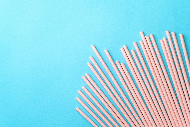 Biodegradable spotted pink paper straw set on blue table background design concept of environmental protection for Earth Day