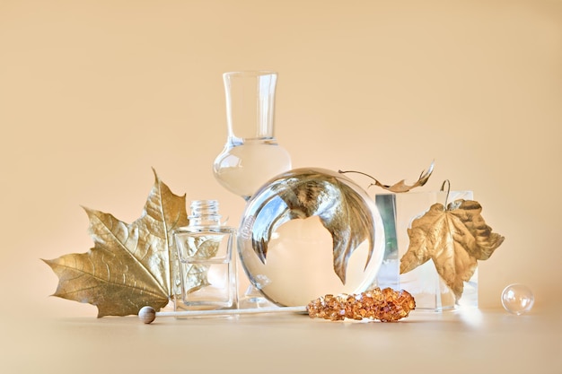 Biophilic Autumn background Gilded gold maple leaves distorted by transparent glass jars small bottles Monocholored orange beige floral elements with reflections