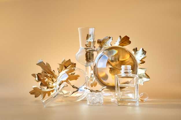 Biophilic Autumn background Gilded gold maple leaves distorted by transparent glass jars small bottles Monocholored orange beige floral elements with reflections