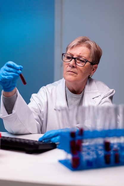 Biotechnologist senior doctor analysing a blood tube for medical investigation