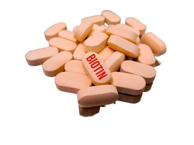 Biotin vitamin B7 white pill tablet on yellow background is vitamin involved in metabolic processes.