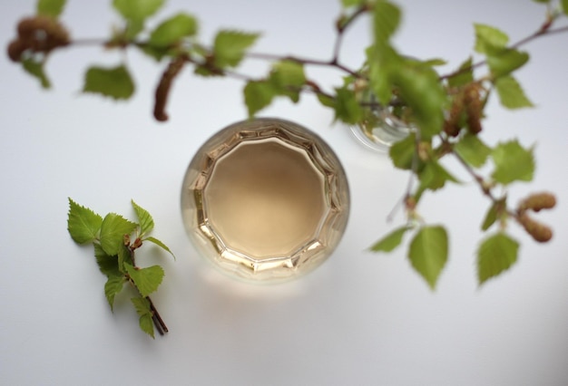 Birch sap in a glass glass with a sprig of blossoming birch