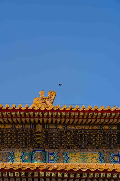 A bird flies over a roof of a temple in beijing.