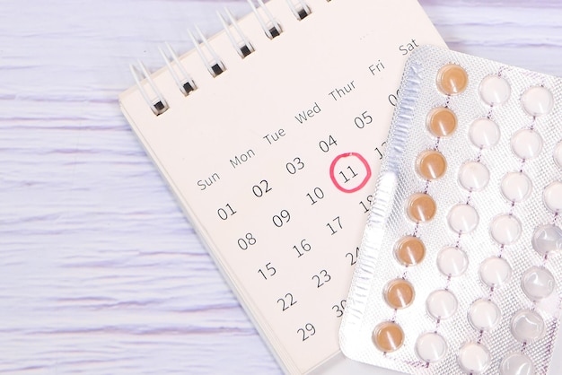 birth control pills calendar and notepad on table