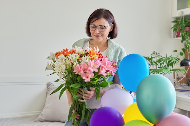 Birthday 45 years old happy female with bouquet of flowers and balloons