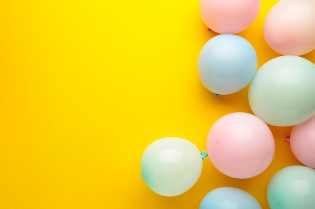 Birthday background with colorful balloons on yellow background top view