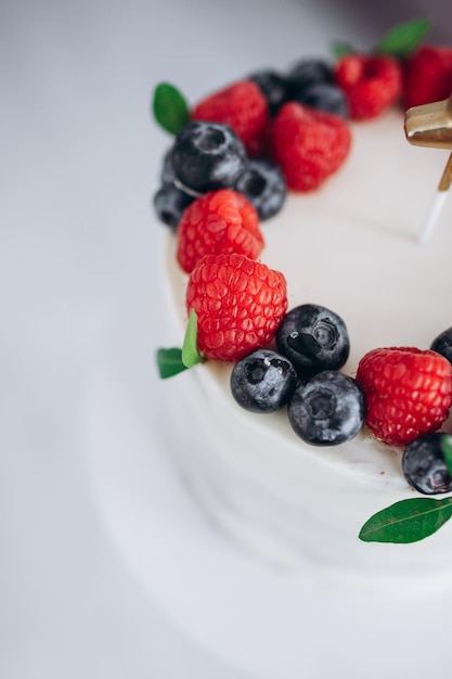 Birthday cake with berries raspberry and blueberrychildrens hands