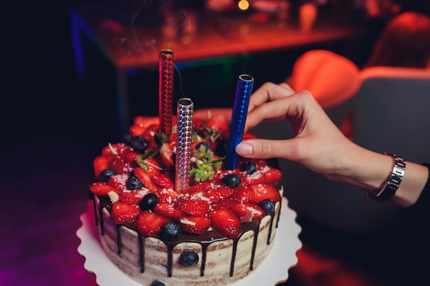 Birthday cake with candles Candles on cake Cake for holiday Beautiful white cake with strawberries on dark background Vertical photo