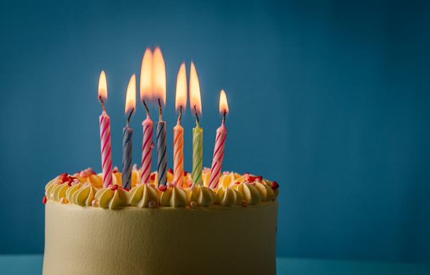 Photo birthday cake  with colorful candles on blue colour background