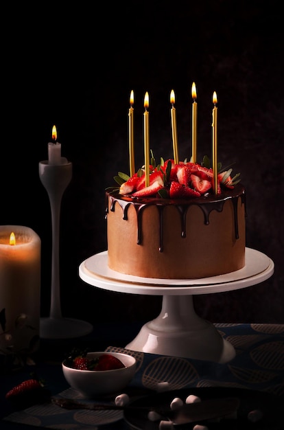 Birthday chocolate cake with candles Candles on top of a birthday cake with strawberry black background