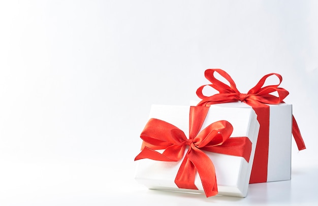 Birthday or Christmas concept, Red ribbon satin bow and white gift boxes on white backgrou