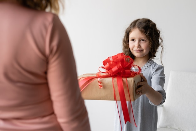 Birthday concept. Girl schoolgirl in a blue dress gives her mom a gift.