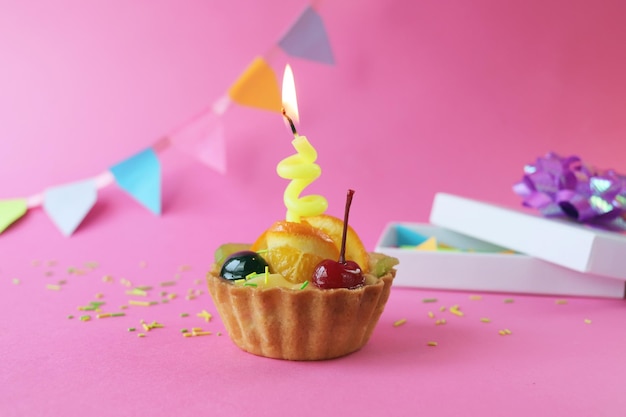 Birthday cupcake decorated with fruit jelly and a burning candle holiday decorations