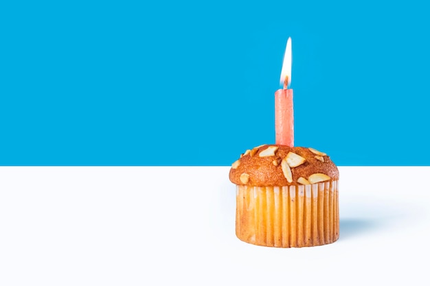 Photo birthday cupcake with glowing candles on white table with blue background copy space for your text